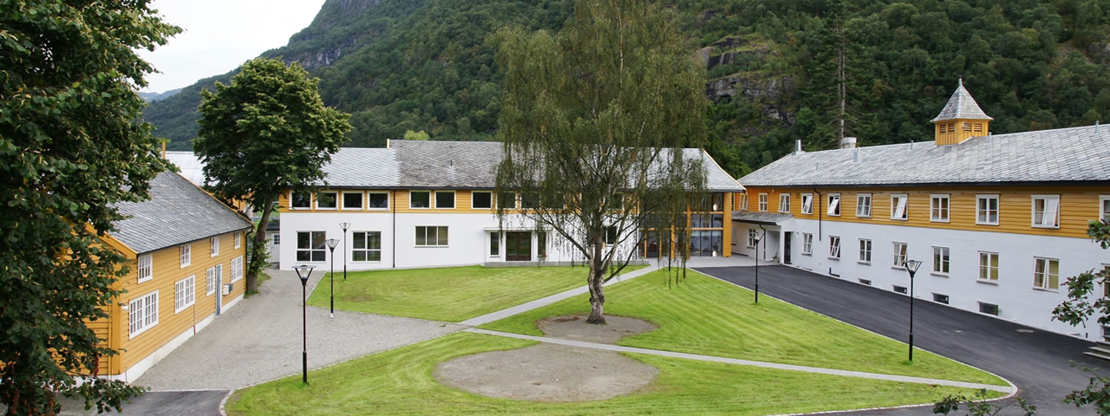 Skulebygningane til Sogn Jord- og Hagebruksskule i Aurland, omgitt av grøne fjell og ope tun.