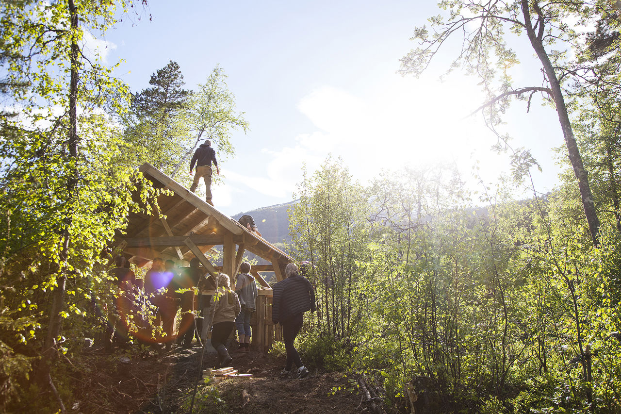 Elevar på Naturbruk ved Sogn Jord- og Hagebruksskule poserer ved ferdigbygd grindbygg i skogen i Aurland.