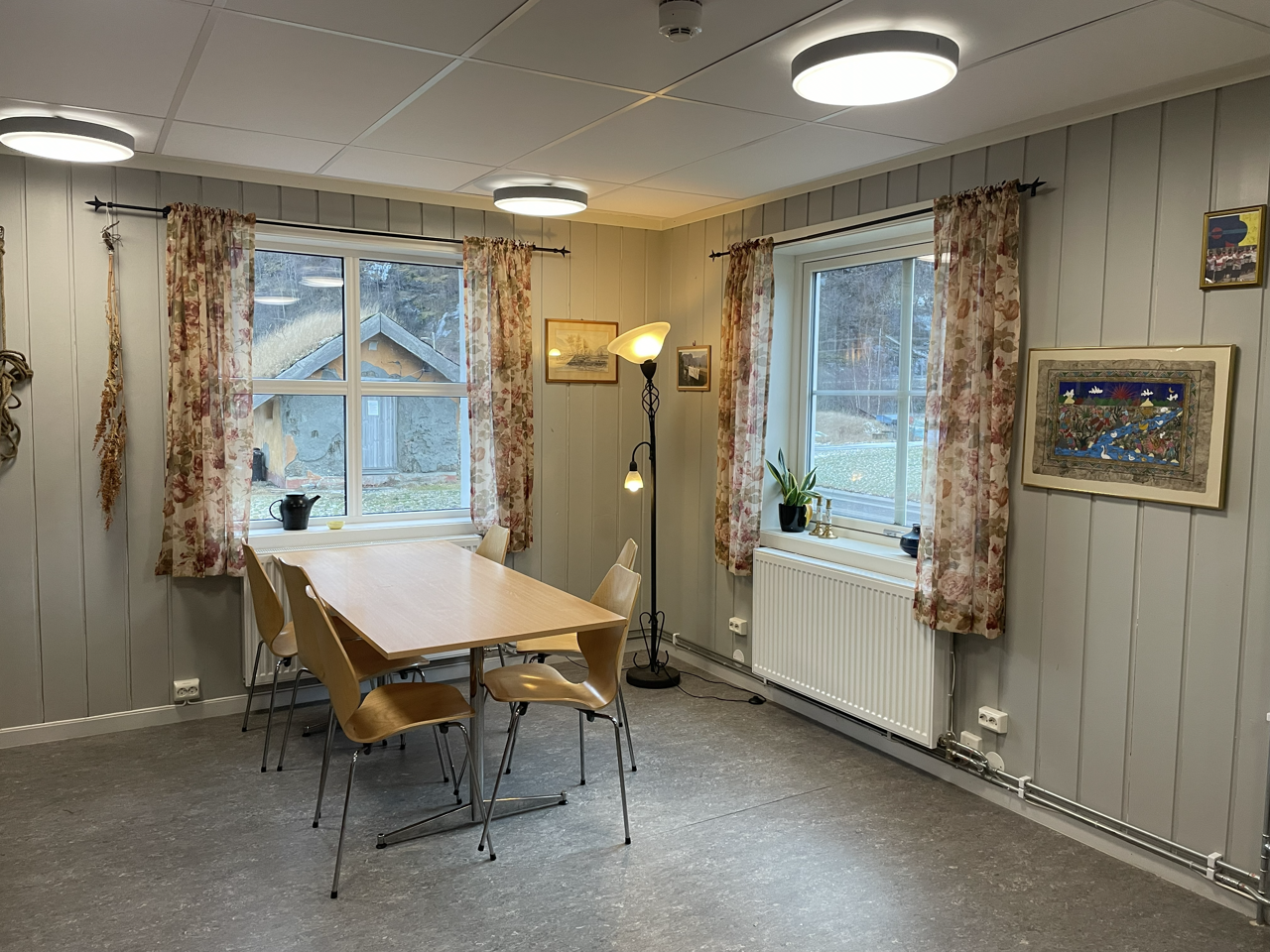 Opphaldsrom på internatet med bord, stolar og store vindauge.