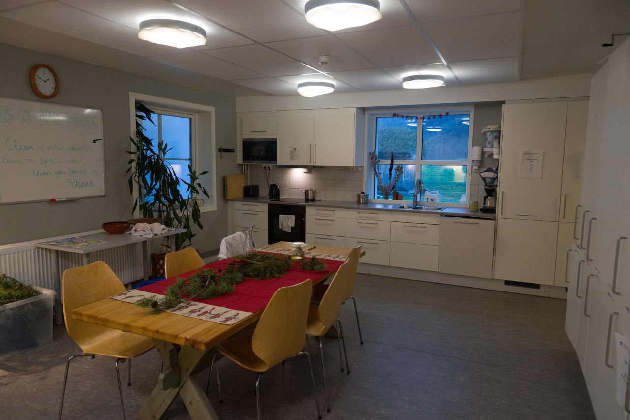 Felleskjøkkenet på internatet ved SJH, med spisebord, kvitt kjøkken, komfyr og store vindauge mot uteområdet.