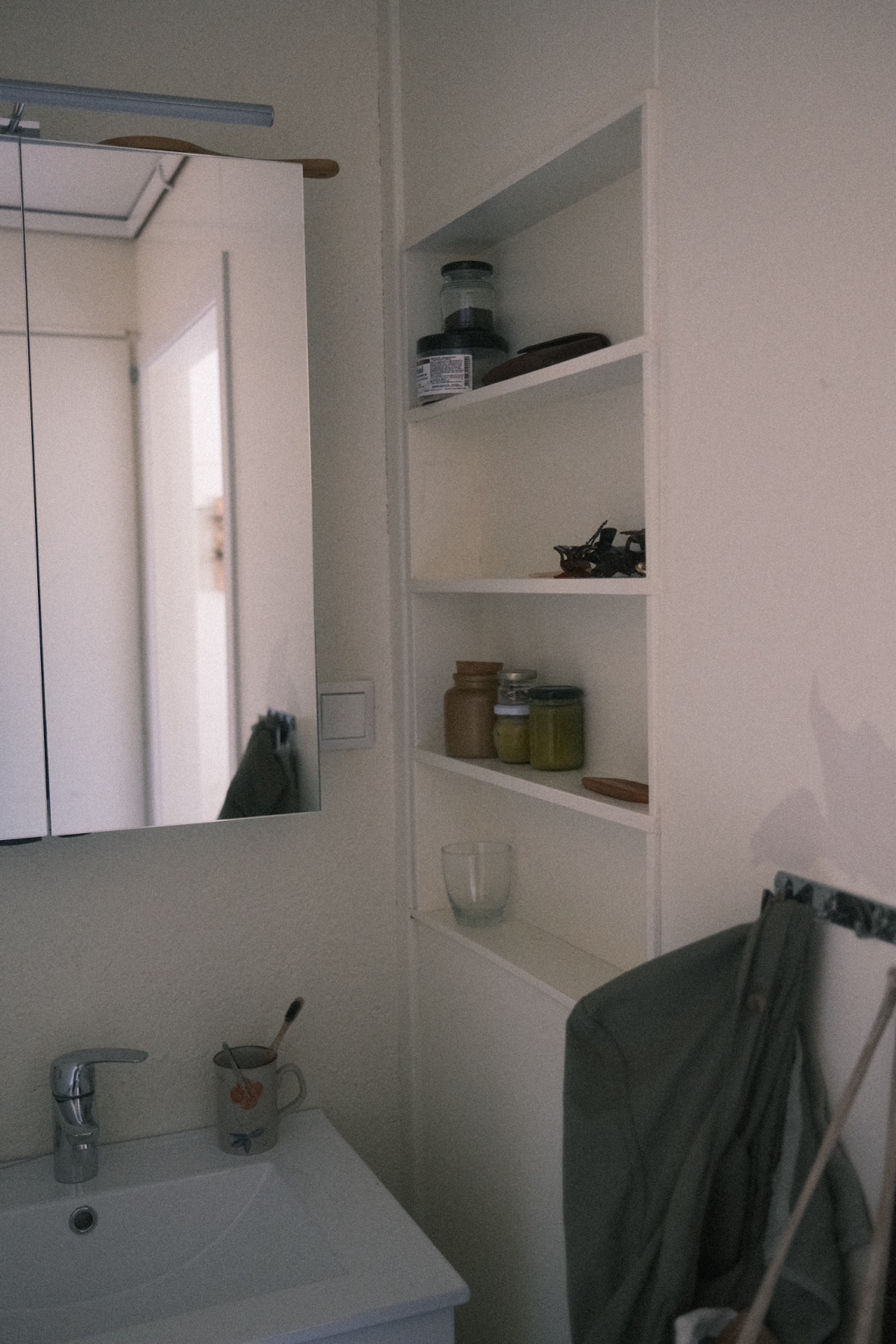 Lite bad på elevrom med vask, spegel og opne hyller.