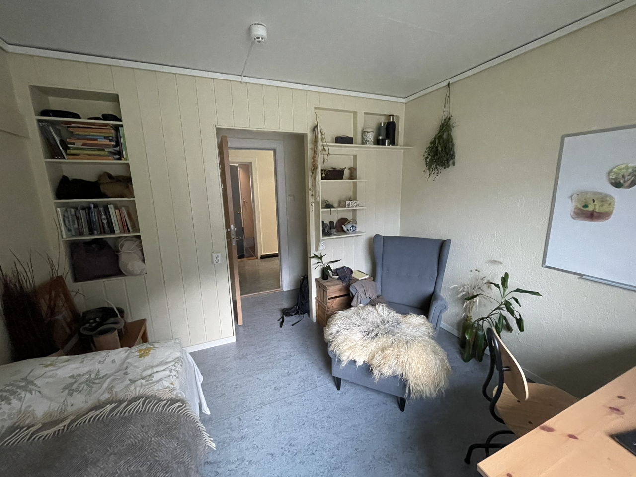 Elevrom på internatet med seng, skrivebord, lenestol og bokhyller.