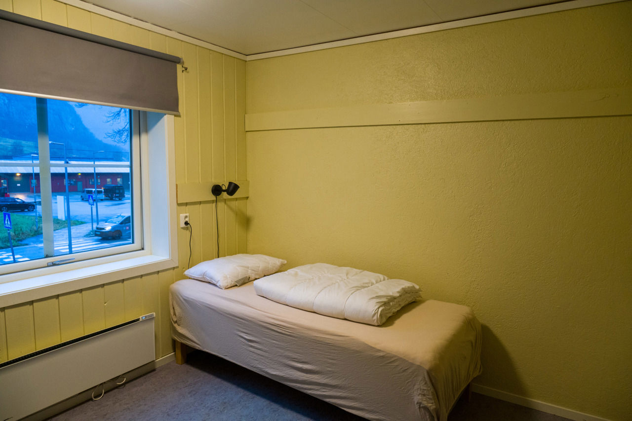Enkelseng med dyne og pute på privatrommet ved internatet på Sogn Jord- og Hagebruksskule, med stort vindu og utsikt mot skuleområdet.