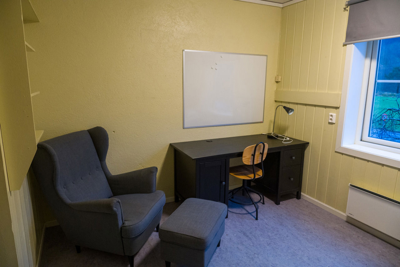 Privatrom på internatet ved Sogn Jord- og Hagebruksskule, med god lenestol, krakk, skrivepult, stol og vindu med utsikt.