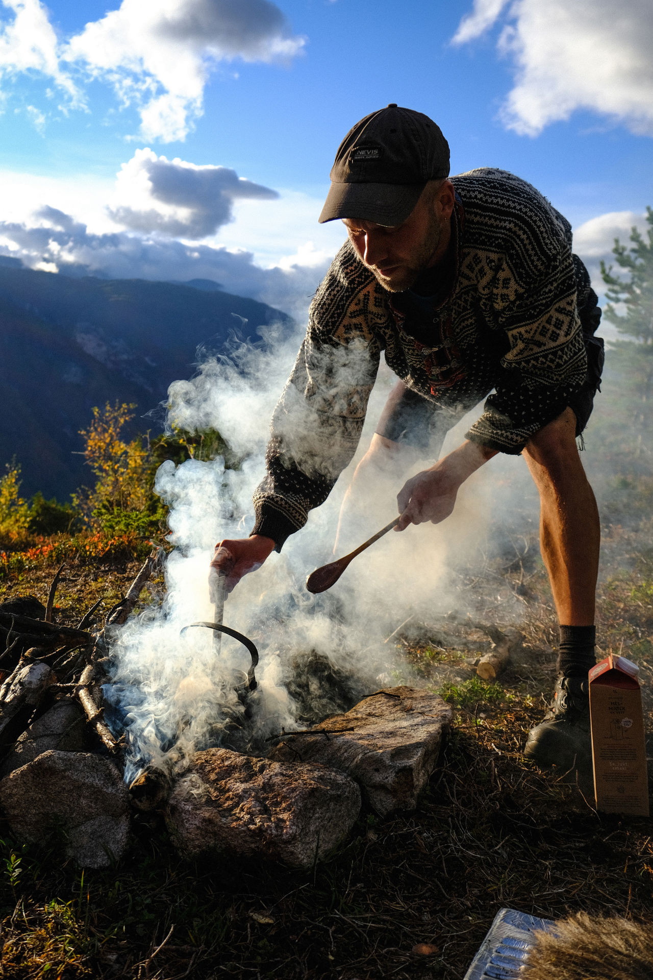 Elev lagar mat over open eld på fjelltur i ettermiddagssol med utsikt over dalen.