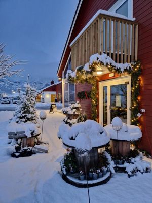 Åpen gårdsbutikk i førjulsstemning, med snø, granbar og varme lys ved inngangen.