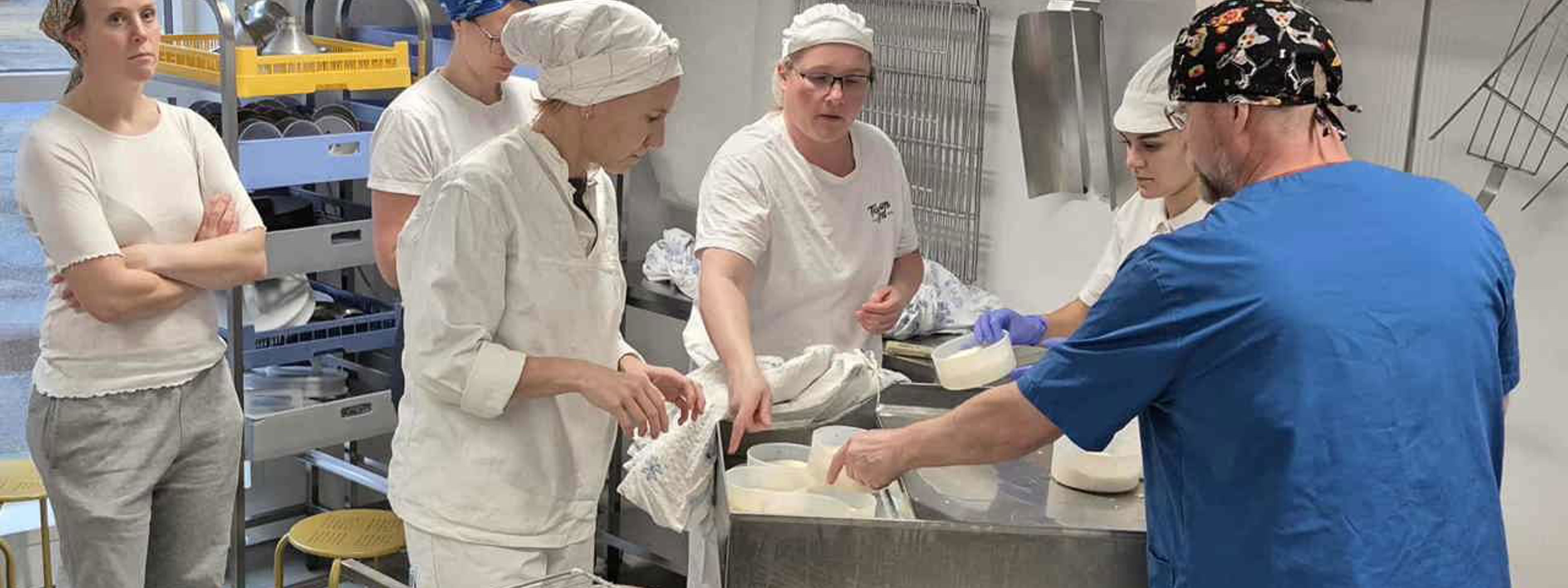 Studentar i fagskulen i handverksysting ved Sogn Jord- og Hagebruksskule får rettleiing i ysting og forming av ostemasse i skuleysteriet.